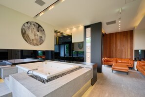 Ein modernes Interieur mit einer großzügigen Badewanne, einer Sitzecke und einem großen Wandbild.
