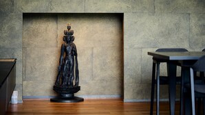 Una estatua en una habitación con pared texturizada y suelo de madera.