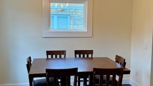 Un coin repas comprenant une table et des chaises, un luminaire au plafond et un tableau encadré accroché au mur.