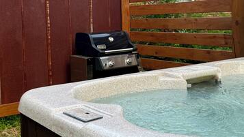 A hot tub with a built-in grill and a smartphone on the edge.