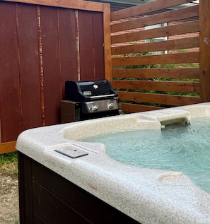 Un bain à remous équipé d’un barbecue intégré et un téléphone intelligent posé sur le bord.
