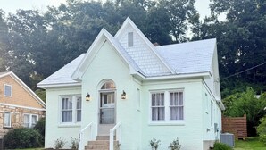 Une maison à deux étages avec un porche à l’avant, une cheminée et un petit jardin.