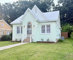 A two-story house with a front porch, a chimney, and a small garden.