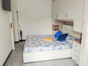 A bedroom with a bed, a dresser, a TV mounted on the wall, and a vase with flowers. - Onda Blu House by Interhome (Loano)