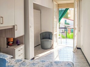 Ein Schlafzimmer mit Bett, Stuhl, Kleiderschrank und Blick ins Freie.