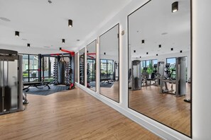 A modern gym with mirrored walls, various exercise equipment, and a wooden floor. - Modern 1BR Apt. Long Term. Downtown. Pool. Parking (Birmingham)