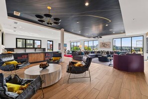 A spacious living area with a modern design, featuring a large seating area, a kitchen, and large windows offering a city view. - Modern 1BR Apt. Long Term. Downtown. Pool. Parking (Birmingham)