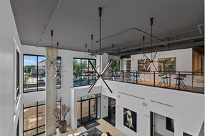 A multi-level interior with large windows, exposed ceilings, and modern lighting fixtures. - Modern 1BR Apt. Long Term. Downtown. Pool. Parking (Birmingham)