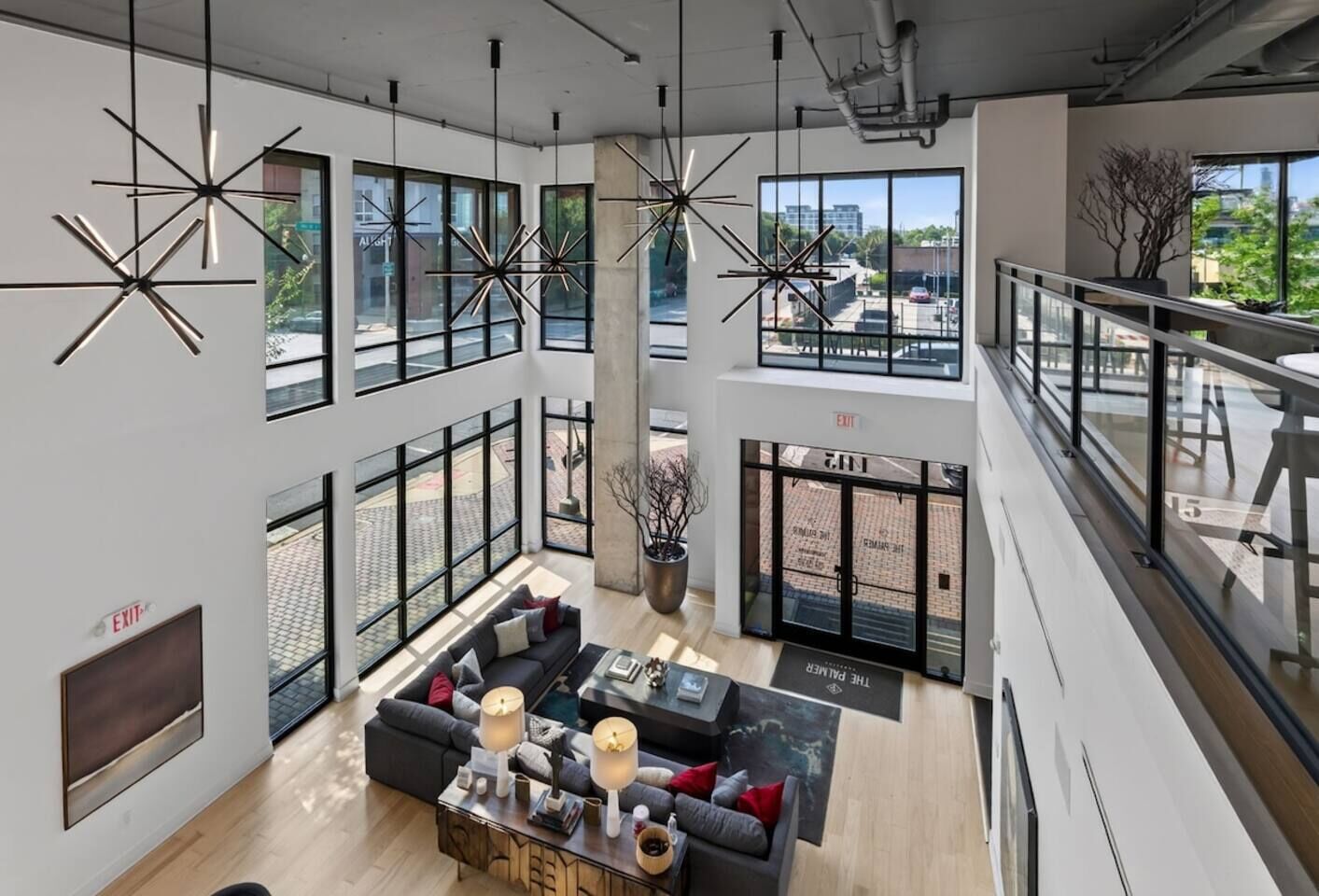 A spacious lobby with a high ceiling, large windows, and a modern chandelier.