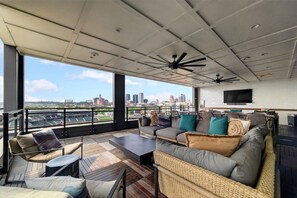 Eine Dachterrasse mit Blick auf die Stadt, ein großes Sofa und ein Flachbildfernseher.