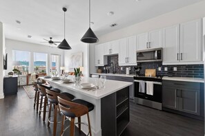 A modern kitchen with a central island, bar stools, and a view of the city. - Modern 1BR Apt. Long Term. Downtown. Pool. Parking (Birmingham)