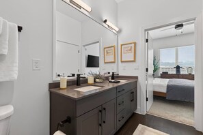 A modern bathroom with a vanity, a large mirror, and a flat-screen TV. - Modern 1BR Apt. Long Term. Downtown. Pool. Parking (Birmingham)