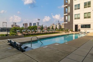 Ein Pool auf dem Dach mit Liegestühlen und einer Skyline im Hintergrund.