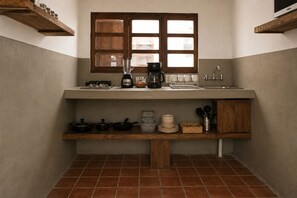 Cozinha compacta com janela, cafeteira e pia.