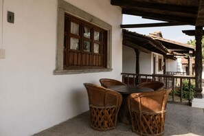 A patio with a table and chairs, a window with shutters, and a balcony railing.