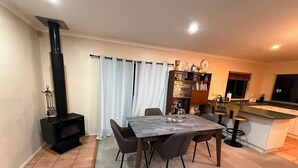 A modern kitchen with a central island, a dining area with a marble table, and a built-in wood stove. - Stay Local, Live Like a Kiwi: Bright & Spacious 3BR Green Home (New Lynn)