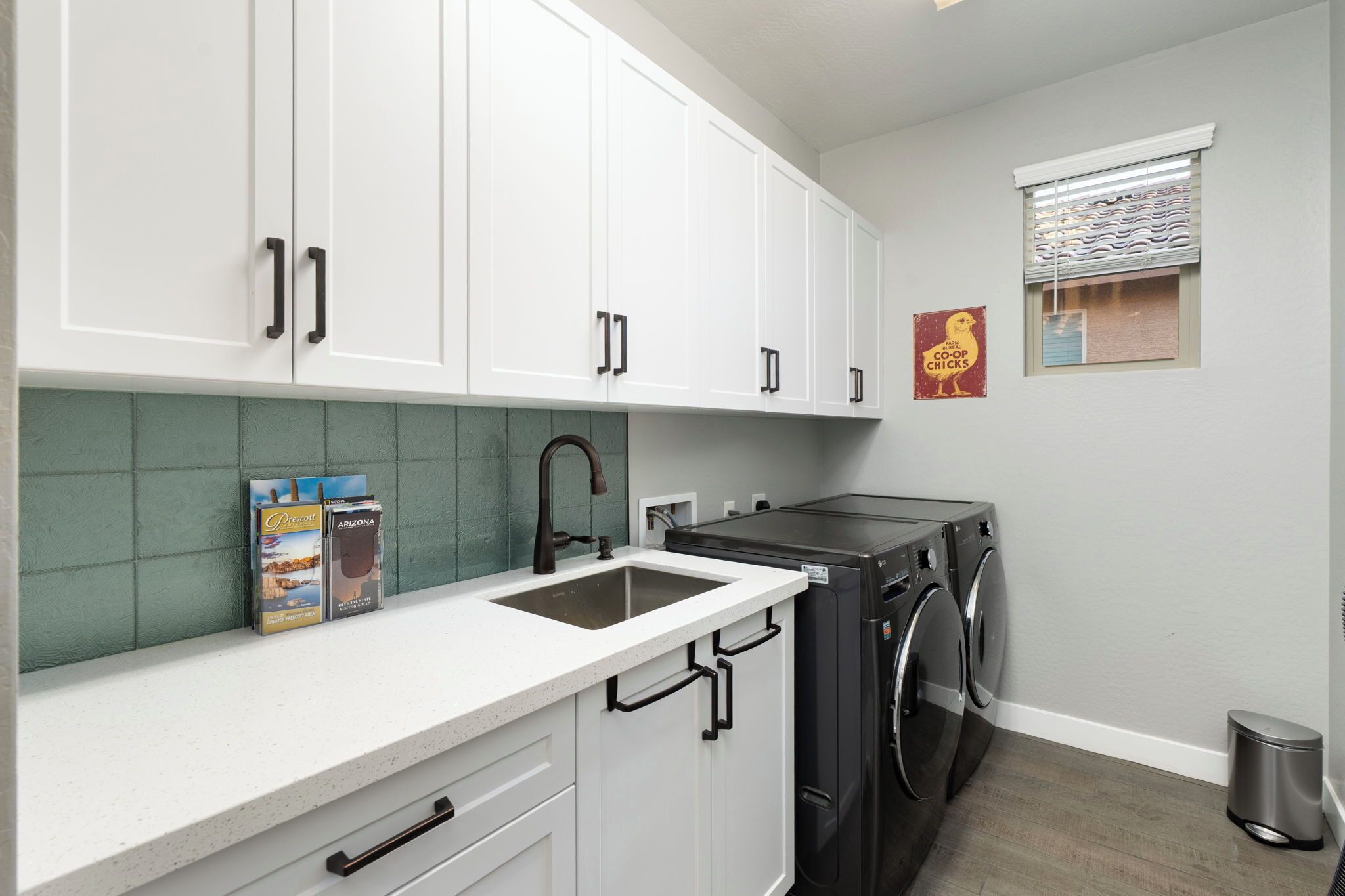 A modern kitchen with white cabinets, a stainless steel sink, and a built-in dishwasher.