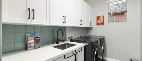 A modern kitchen with white cabinets, a stainless steel sink, and a built-in dishwasher.