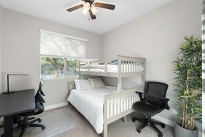A bedroom with bunk beds, a desk, a chair, a ceiling fan, and a window with blinds. - Desert Mountain Views - Quiet Retreat - Hot Tub - Firepit - Quiet Neighborhood (Goodyear)
