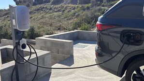 A car connected to a charging station in an outdoor setting.
