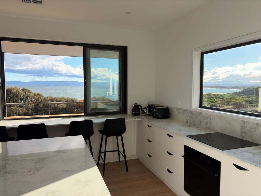 Una cucina moderna con ampie finestre, un piano di lavoro in marmo e vista sul mare.