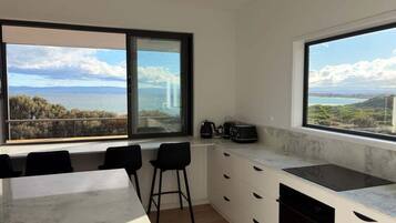Una cucina moderna con ampie finestre, un piano di lavoro in marmo e vista sul mare.