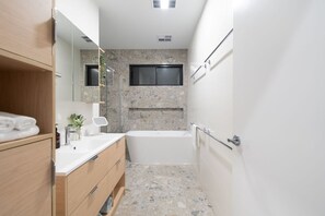 A modern bathroom with a freestanding bathtub, a vanity with a mirror, and a shower area. - Beach Break - Freycinet Holiday Houses (Coles Bay)