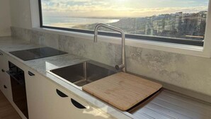 A kitchen with a large window, a sink, and a wooden cutting board.