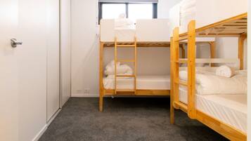 A bunk bed room with a window, carpeted floor, and a door.