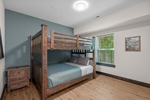 A bunk bed with a wooden frame, a bedside table, and a window with blinds. - More than a getaway, your best Branson family vacation memories start right here! (Hollister)