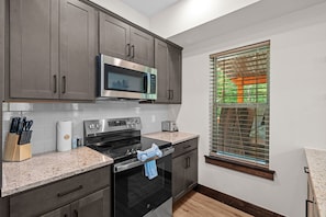 A modern kitchen with stainless steel appliances, a microwave, and a window with blinds. - More than a getaway, your best Branson family vacation memories start right here! (Hollister)