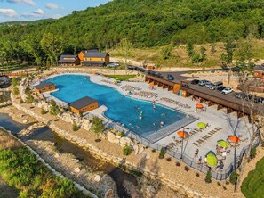 A resort with a large swimming pool, outdoor seating areas, and a mountain backdrop. - More than a getaway, your best Branson family vacation memories start right here! (Hollister)