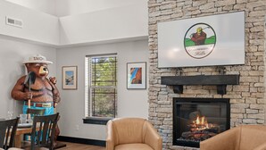 Een woonkamer met een stenen openhaard, een beerbeeld en een ingelijst logo aan de muur.