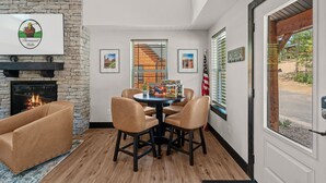 Een kamer met een stenen openhaard, een ronde tafel met stoelen, en ingelijste foto’s aan de muur, plus een Amerikaanse vlag.