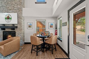 A room with a stone fireplace, a round table with chairs, framed pictures on the wall, and an American flag. - More than a getaway, your best Branson family vacation memories start right here! (Hollister)