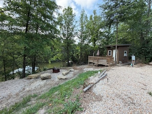 A cabin with a deck overlooking a lake, surrounded by trees.