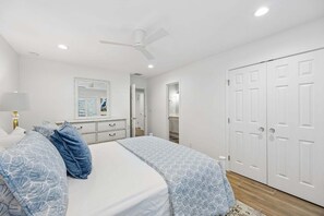 Ein Schlafzimmer mit Bett, Schminktisch, Spiegel, Deckenventilator und Kleiderschrank.