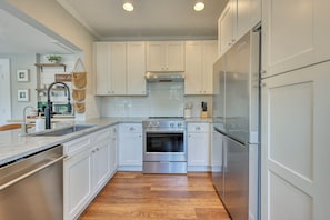 A modern kitchen with white cabinetry, a stainless steel refrigerator, and a built-in oven. - Parkside 1922 - Steps to Boone Park & Avondale Shops (Jacksonville)