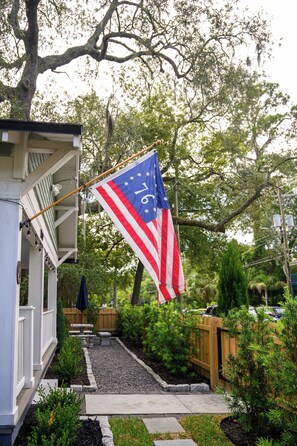 En boligejendom med flagstang og amerikansk flag, omgivet af en have med forskellige planter og et træhegn.