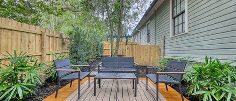Un patio al aire libre con terraza de madera, una mesa de metal y cuatro sillas.