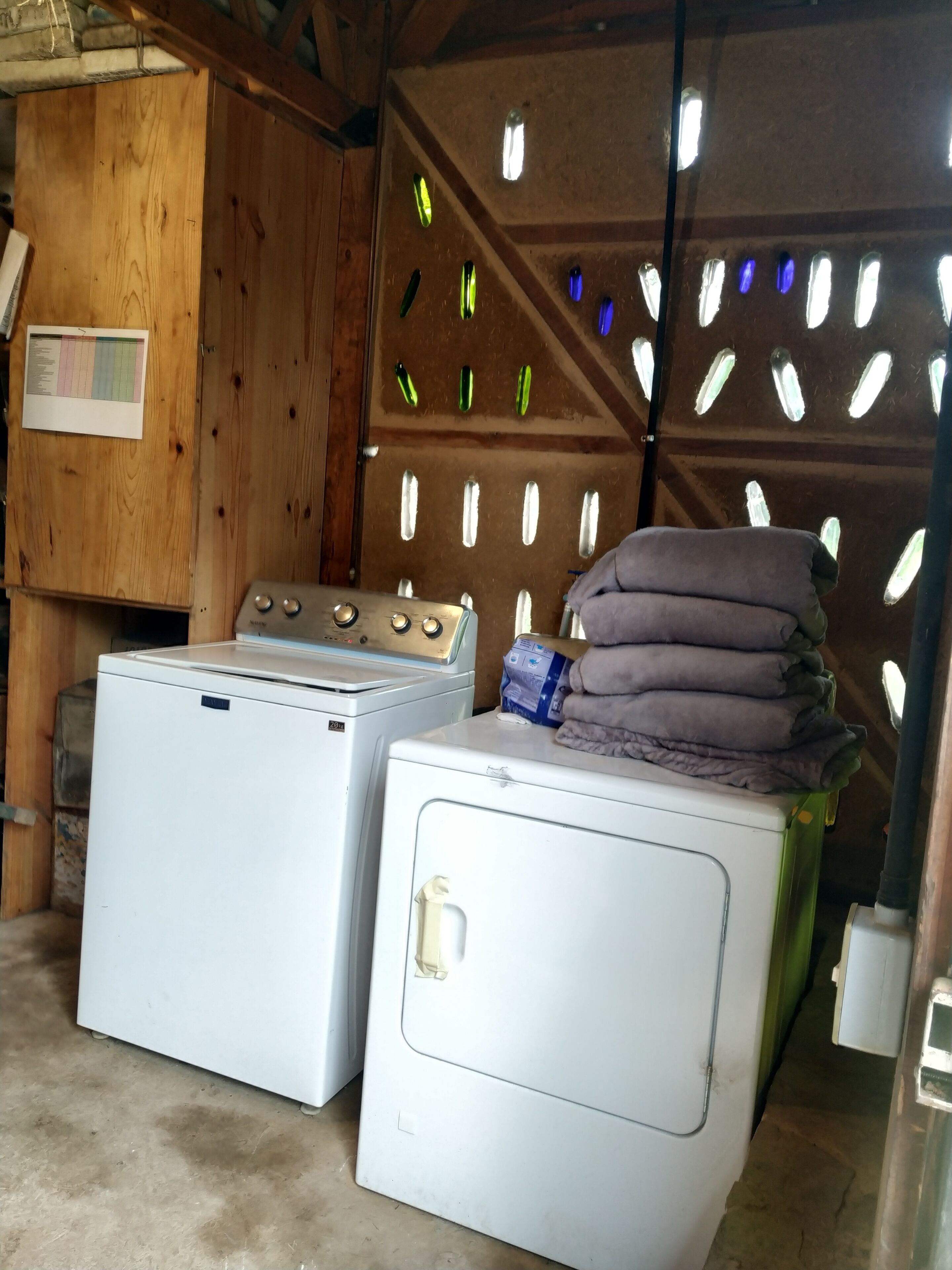 A laundry area with two white washing machines and a stack of folded towels on one of them.