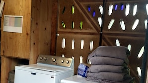 A laundry area with two white washing machines and a stack of folded towels on one of them.