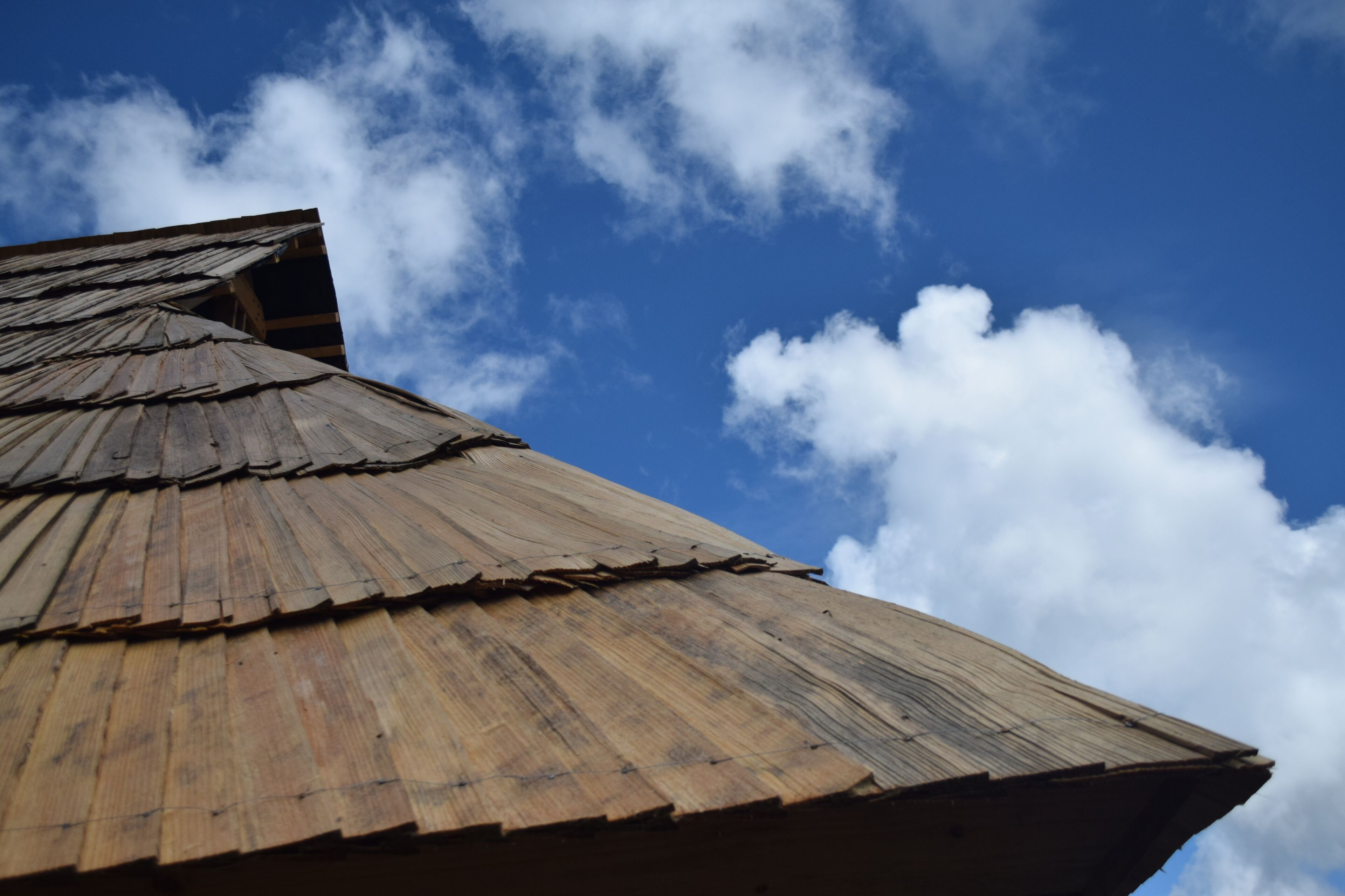 A wooden structure with a sloped roof against a clear sky.