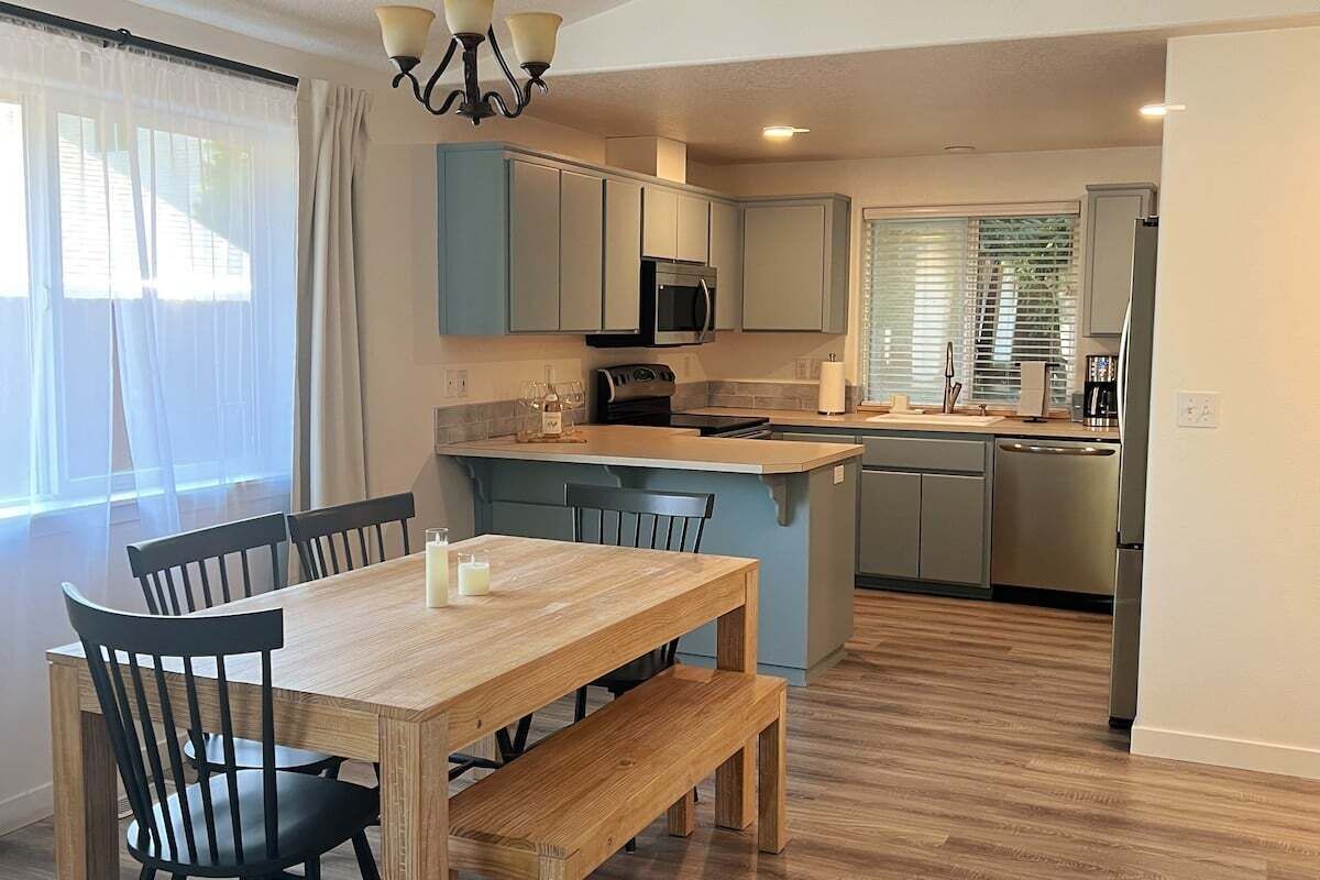 Een moderne keuken met een eethoek, met een houten tafel, stoelen en een inbouwmagnetron.