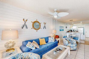 Ein Wohnzimmer mit einem blauen Sofa, einem Couchtisch und einem Essbereich mit Stühlen.