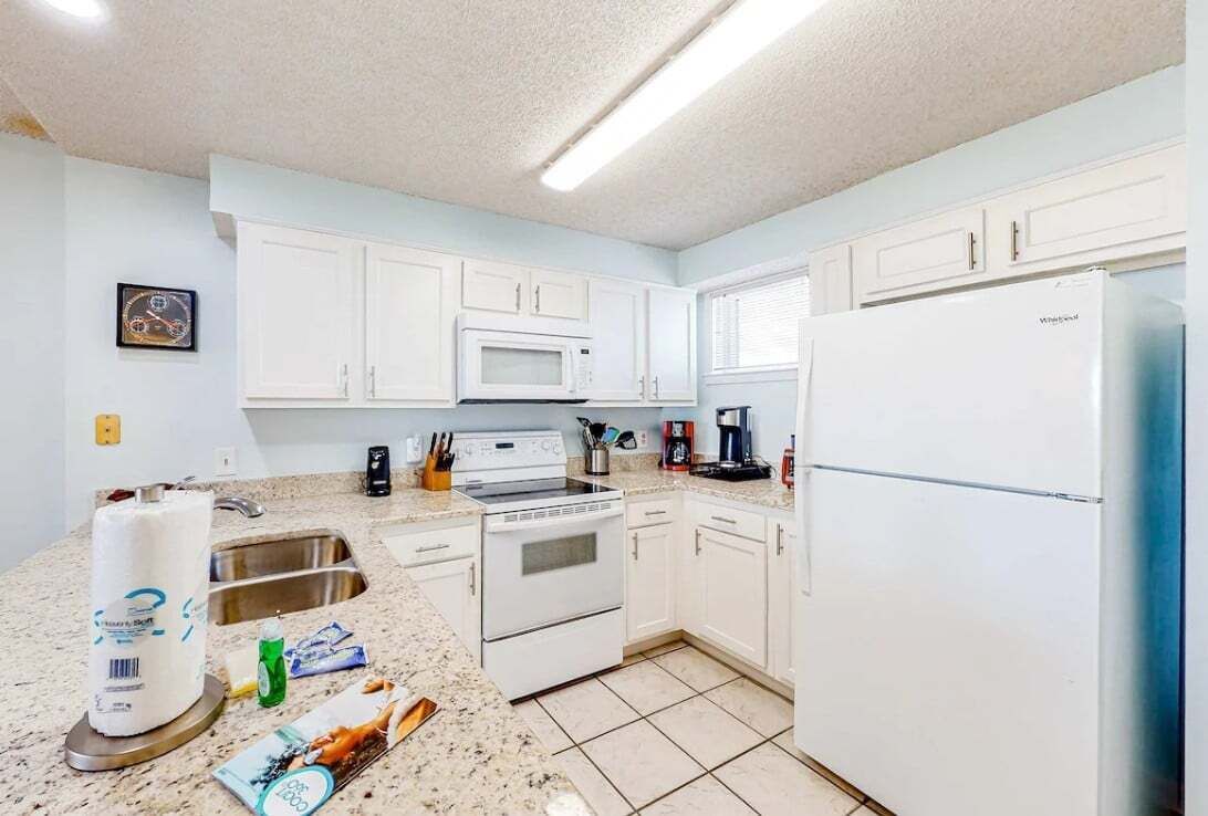 A kitchen with white cabinets, a microwave, a stove, and a refrigerator.