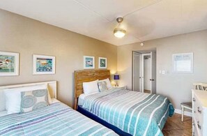 Ein Hotelzimmer mit zwei Betten, einem Holzkopfende, einem Nachttisch und Wandbildern.