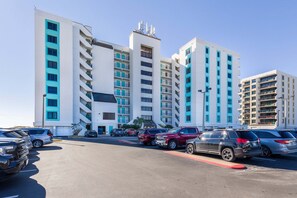 A multi-story hotel with a parking lot in front. - Island Winds East 809 | Walk to the HangOut! | Gulf Front | Beachside Pool | My Beach Getaways (Gulf Shores)