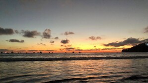 Un atardecer sobre el océano con barcos a lo lejos.