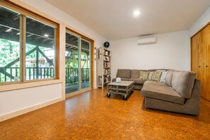 A spacious living room with a large window, a sliding glass door, a bookshelf, a sofa, and a coffee table. - Riverfront 3-bedroom house in enchanting Mount Hood Village with private hot tub (Mount Hood Village)